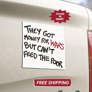 May include: A white square sticker or magnet with the text "THEY GOT MONEY FOR WARS BUT CAN'T FEED THE POOR" in black and red. The sticker is affixed to a vehicle.