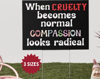 May include: Black yard sign with white text: "When cruelty becomes normal, compassion looks radical." The word "cruelty" is red, and "compassion" has pastel colors. A red starburst graphic says "3 sizes."