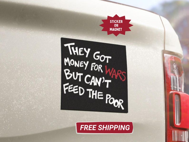 May include: Black square sticker or magnet with white text reading "THEY GOT MONEY FOR WARS BUT CAN'T FEED THE POOR." The word "WARS" is in red. The sticker is affixed to a white vehicle.