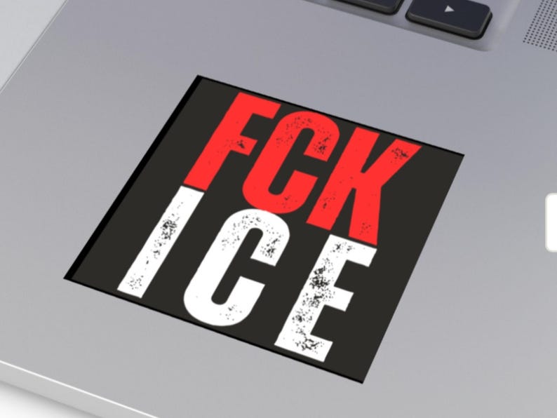 May include: A black square sticker with the words "FCK ICE" in bold, distressed white and red letters. The sticker is placed on a silver laptop.