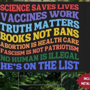 Op de afbeelding: Een zwart tuinbord met kleurrijke tekst met de tekst "WETENSCHAP REDT LEVENS, VACCINS WERKEN, WAARHEID DOET ERTOE, GEEN BOEKEN, ABORTUS IS GEZONDHEIDSZORG, FASCISME IS GEEN PATRIOTISME, GEEN MENS IS ILLEGAAL, HIJ STAAT OP DE LIJST." Inclusief een metalen paal.