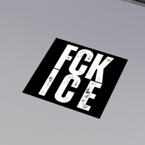 May include: A black square sticker with the white text "FCK ICE" in a distressed font. The sticker is angled on a light grey surface.