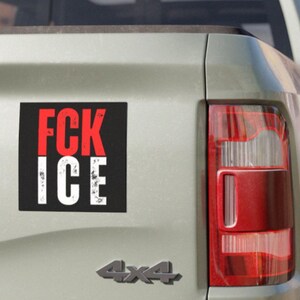 May include: A black and red sticker with the words "FCK ICE" in white lettering is attached to the rear of a light-coloured vehicle. The vehicle's taillight is visible on the right, and the 4x4 emblem is below the sticker.