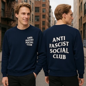 K&ouml;nnte beinhalten: Marineblaues Sweatshirt mit dem wei&szlig;en Aufdruck "ANTI FASCIST SOCIAL CLUB" auf der Vorder- und R&uuml;ckseite. Das Sweatshirt hat einen Rundhalsausschnitt.