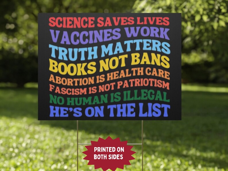 Op de afbeelding: Zwart bord met kleurrijke tekst: "WETENSCHAP REDT LEVENS, VACCINS WERKEN, WAARHEID DOET ERTOE, BOEKEN GEEN VERBODEN, ABORTUS IS GEZONDHEIDSZORG, FASCISME IS GEEN PATRIOTISME, GEEN MENS IS ILLEGAAL, HIJ STAAT OP DE LIJST". Bedrukt aan beide zijden.
