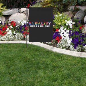 May include: A black garden flag with the text "EQUALITY HURTS NO ONE" in rainbow colors. The flag is displayed in a garden setting with flowers.
