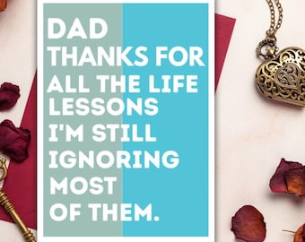 May include: A rectangular greeting card with a split background of sage green and bright blue. The white text reads: DAD THANKS FOR ALL THE LIFE LESSONS I'M STILL IGNORING MOST OF THEM. The card is centered on a dark red envelope.