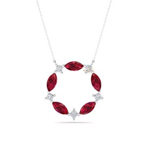 May include: A silver necklace featuring a circular pendant. The pendant is adorned with marquise-cut red gemstones and square-cut clear gemstones, creating a halo design. The necklace is displayed against a white background.