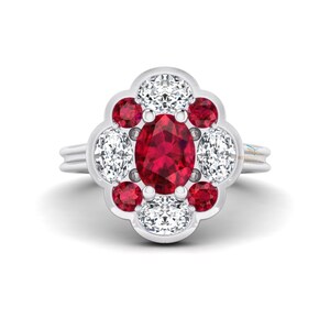 May include: A silver ring featuring a central oval ruby surrounded by a floral arrangement of smaller red rubies and white diamonds. The ring's design is elegant and eye-catching, perfect for special occasions.