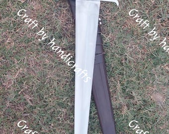 May include: A long, silver sword with a brown handle and a leather sheath. The sword has a crossguard and a rounded pommel. The sheath is dark brown with a silver tip. The text "Craft by handicrafts" is visible.