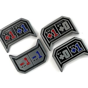 May include: Four gray metal tokens with black borders and various red and blue numbers and symbols. The tokens have a geometric design and are arranged on a white surface. The tokens appear to be game pieces.