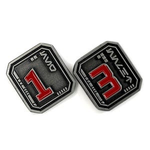 May include: Two metallic grey and red number badges. One badge displays the number 1, and the other displays the number 3. The numbers are in red, and the badges have a rectangular shape with rounded corners. The badges have a futuristic design.