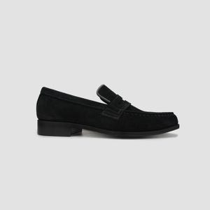 May include: Black suede penny loafers with a low heel. The shoes have a classic design with a strap across the vamp and a rounded toe. The loafers are a versatile footwear option.