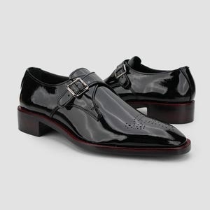 May include: Pair of black patent leather dress shoes with a buckle closure. The shoes have a low heel and a decorative perforated design on the toe. The soles have a red trim.