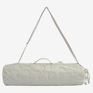 Puede incluir: Una bolsa de esterilla de yoga de color beige claro con una correa para el hombro y un asa. La bolsa cil&iacute;ndrica est&aacute; hecha de una tela texturizada y tiene una peque&ntilde;a etiqueta cerca del asa. La correa es ajustable y la bolsa tiene un cierre de cord&oacute;n.