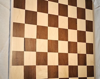 May include: A wooden chessboard with a light brown and dark brown checkered pattern. The board is made of maple and walnut wood.