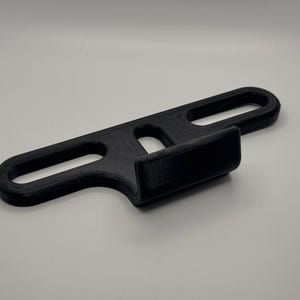 May include: A black plastic bike rack mount with a hook for hanging a bike.