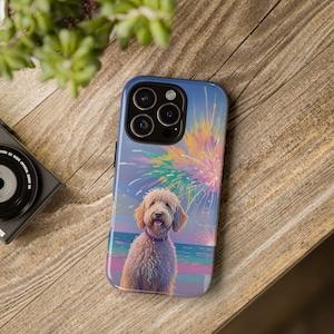 May include: A blue phone case featuring a golden doodle dog with a purple collar, set against a backdrop of fireworks and a beach scene. The case has a glossy finish and a camera cutout.