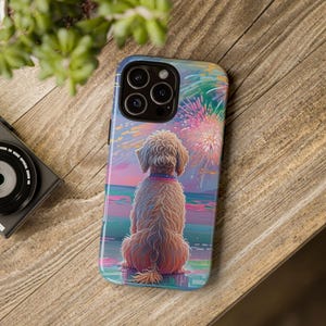 May include: A phone case featuring a dog watching fireworks. The illustration shows a light brown dog with a pink collar, facing away from the viewer, with a colorful fireworks display in the background. The case is on a wooden surface.