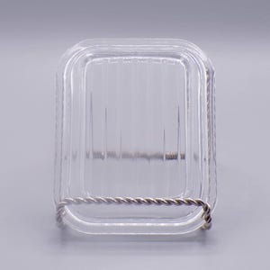 May include: A clear glass square dish with a silver wire rim. The dish has a ribbed pattern on the bottom.