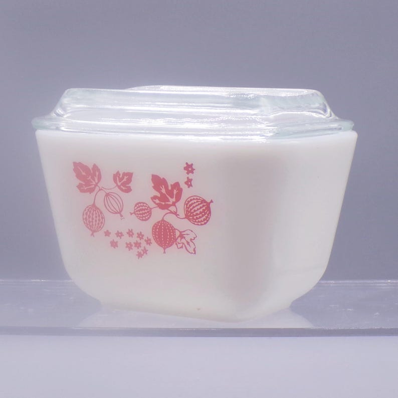 May include: White glass baking dish with a pink floral design of gooseberries and leaves. The dish has a clear glass lid.