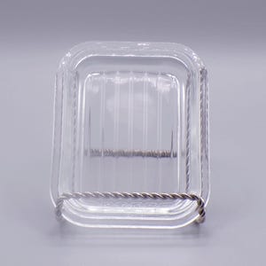 May include: A clear glass square dish with a wire rim. The dish has a ribbed pattern on the bottom.