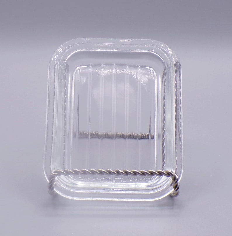 May include: A clear glass square dish with a wire rim. The dish has a ribbed pattern on the bottom.