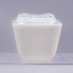 May include: White glass storage container with a clear glass lid. The container has a square shape with rounded corners.