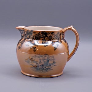 May include: A brown ceramic pitcher with a floral design around the top and a black and white scene of ships on the bottom.