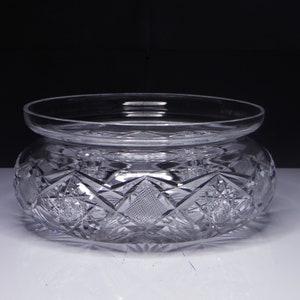 May include: A clear glass bowl with a cut glass design. The bowl has a wide, flat base and a rounded, slightly flared top.