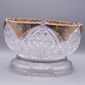 May include: A clear glass bowl with a cut glass design and a gold rim. The bowl is on a clear glass pedestal.