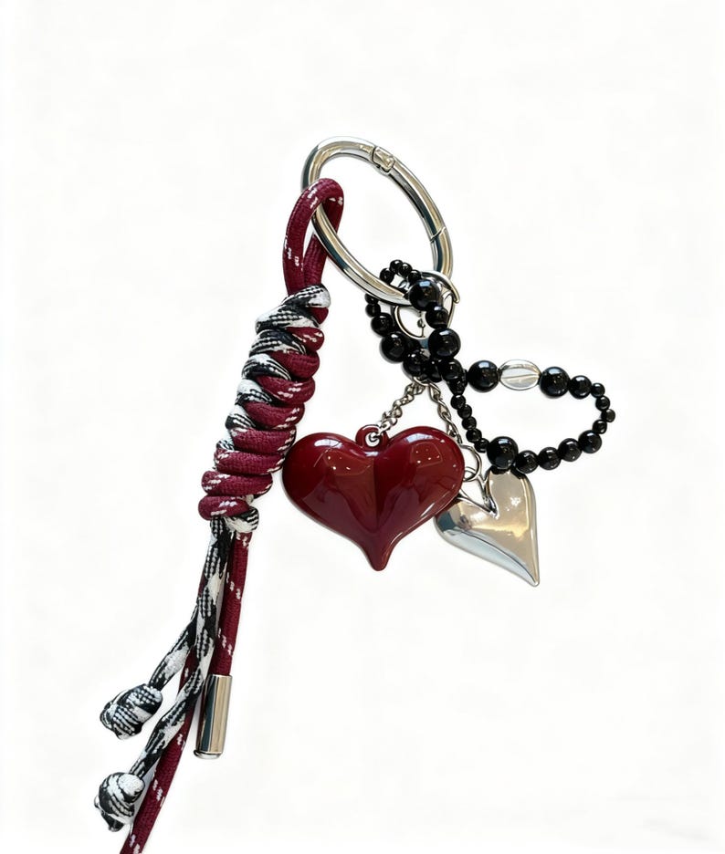 Peut inclure: Un porte-cl&eacute;s avec un charm en forme de c&oelig;ur bordeaux, un charm en forme de c&oelig;ur argent&eacute; et des perles noires. Il comprend un cordon tress&eacute; bordeaux, noir et blanc et un fermoir argent&eacute;.