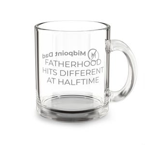 Puede incluir: Una taza de café de vidrio transparente con asa. La taza presenta el texto "FATHERHOOD HITS DIFFERENT AT HALFTIME" en gris, junto con un logotipo. La taza está vacía y se encuentra sobre una superficie blanca.