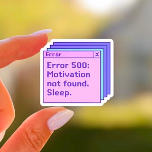 May include: A sticker with a retro computer error message. The text reads "Error 500: Motivation not found. Sleep." The sticker has a pink background with a blue and purple border. The sticker is held by a person.