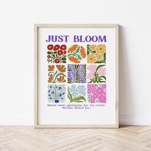 Puede incluir: Una impresión enmarcada con el texto "JUST BLOOM" en letras moradas. La impresión presenta un diseño colorido de varias flores en un patrón de cuadrícula. El texto debajo del diseño dice "La naturaleza nunca se disculpa por sus colores. Tú tampoco deberías."