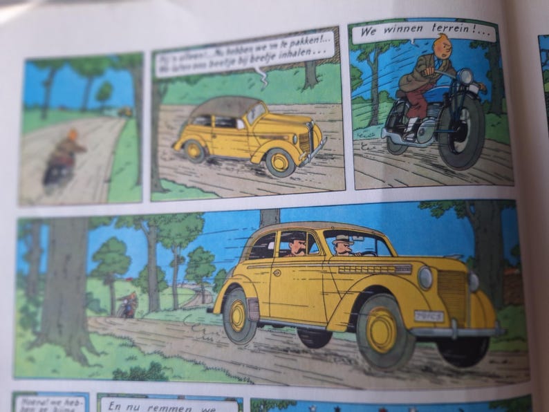 May include: Comic strip panels featuring a yellow car and a motorcycle racing on a road. The text in the speech bubbles reads "We win terrain!" and other Dutch phrases. The style is reminiscent of classic comic book art.