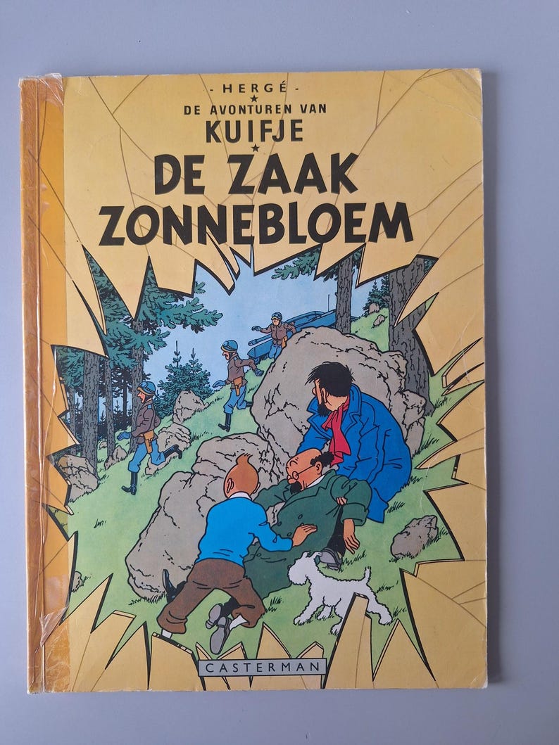 May include: A vintage comic book titled "De Zaak Zonnebloem" by Herg&eacute;. The cover features a colorful illustration of characters in a forest setting, with text in Dutch. The book is in good condition, with a yellow cover and a Casterman logo.
