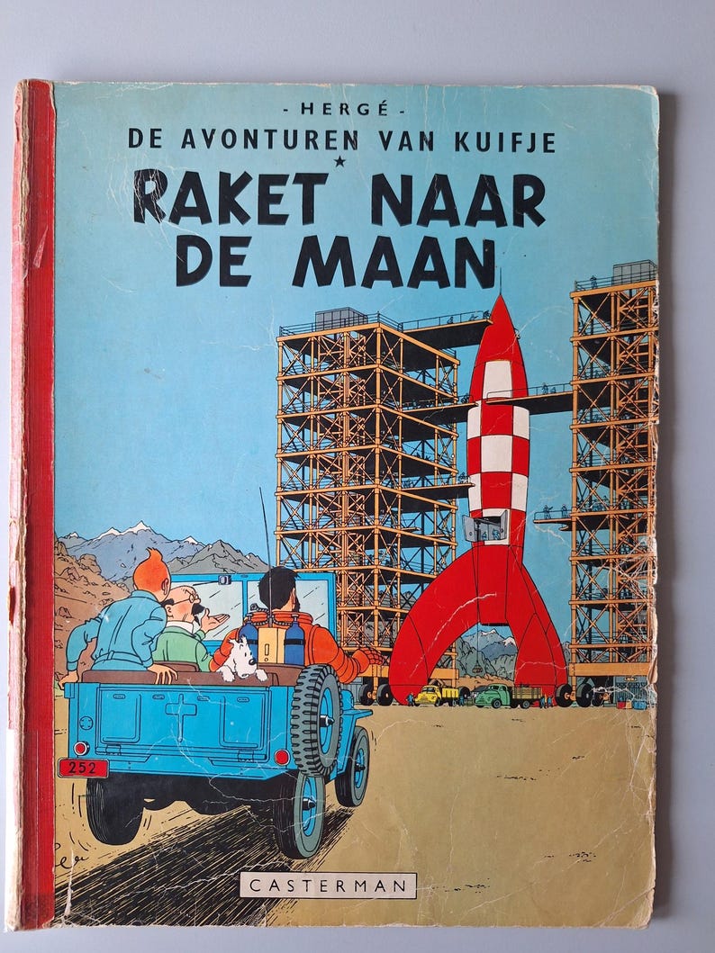 May include: Vintage comic book cover featuring a red and white rocket, blue jeep, and the text "RAKET NAAR DE MAAN." The cover has a blue sky background and illustrations of a rocket launch site.