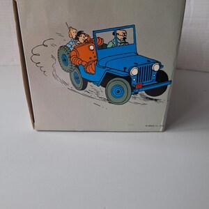 May include: A white ceramic mug with a black handle and the text "But First, Coffee" in a bold, black font. The mug is set against a blurred background, highlighting its clean design.