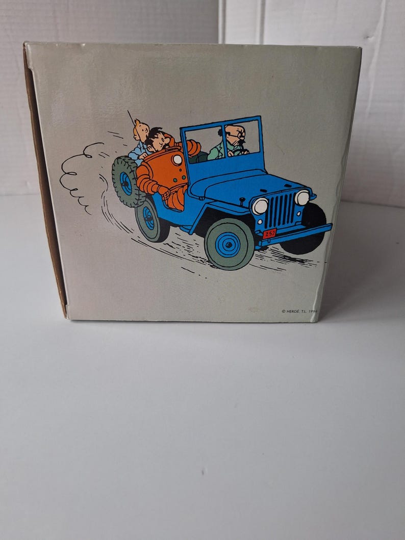 May include: A white ceramic mug with a black handle and the text "But First, Coffee" in a bold, black font. The mug is set against a blurred background, highlighting its clean design.