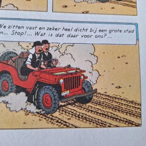 May include: Comic strip panel featuring two men in a red jeep driving on a dirt road. The jeep has large tires and a spare tire on the back. Text in a speech bubble reads, "We are stuck and very close to a big city... Stop!... What is that there for us?"