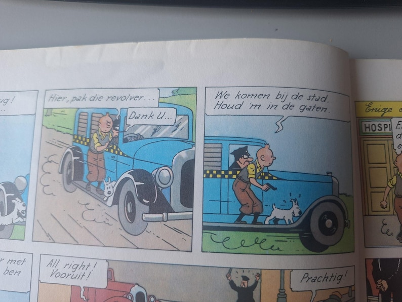 Może przedstawiać: Panel komiksu przedstawiający niebieski samoch&oacute;d z taks&oacute;wką. Przedstawiono dwie postacie, z kt&oacute;rych jedna trzyma broń. Dymki zawierają frazy takie jak "Hier, pak die revolver..." i "Dank U..."