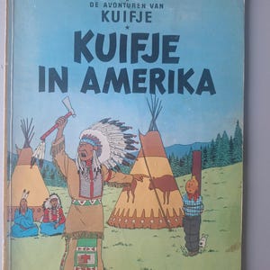 Może przedstawiać: Vintage okładka komiksu zatytułowana "KUIFJE IN AMERICA" w dużych białych literach na tle błękitnego nieba. Okładka zawiera ilustracje Indian, tipi i związanej postaci.