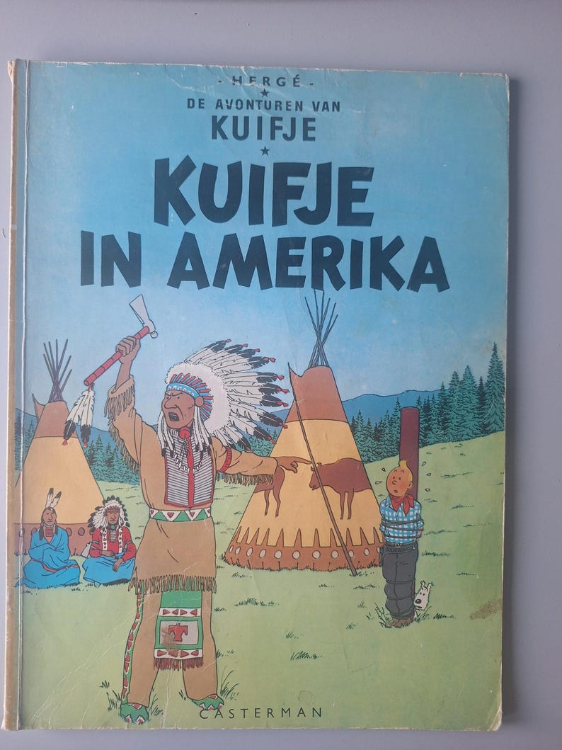 Może przedstawiać: Vintage okładka komiksu zatytułowana "KUIFJE IN AMERICA" w dużych białych literach na tle błękitnego nieba. Okładka zawiera ilustracje Indian, tipi i związanej postaci.