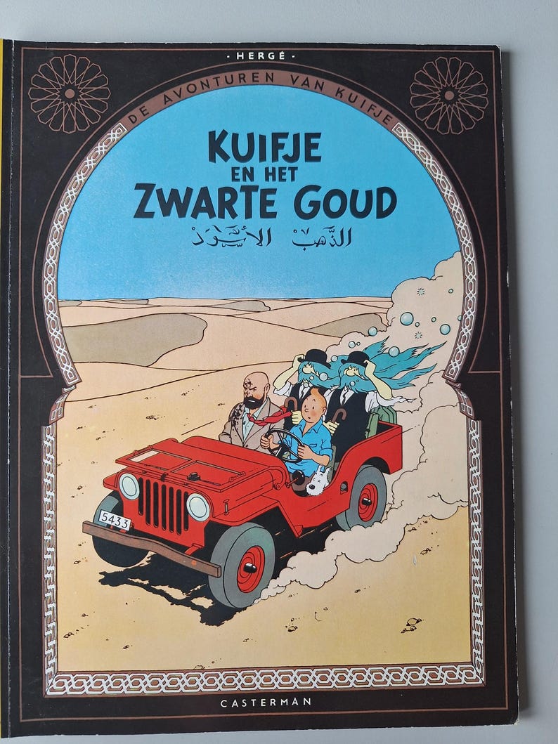 May include: A vintage comic book cover featuring a red jeep driving through a desert landscape. The title "Kuifje en het Zwarte Goud" is displayed in large letters, with additional text in Arabic. The cover has a decorative border.