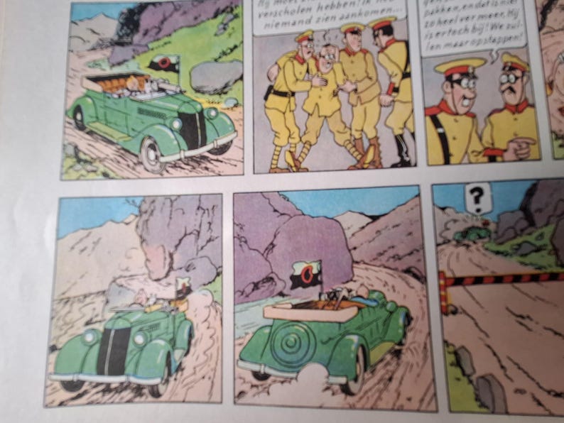 May include: Comic strip panels showing a green vintage convertible car on a winding road. The car has a flag with a black and white emblem. Other panels show characters in yellow uniforms and a mountain landscape.