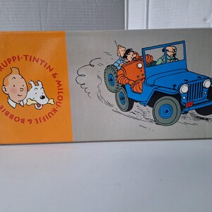 May include: A white ceramic mug with a black handle and the text "But First, Coffee" in a bold, black font. The mug is set against a blurred background, suggesting a cozy setting. The mug appears to be approximately 4 inches tall.