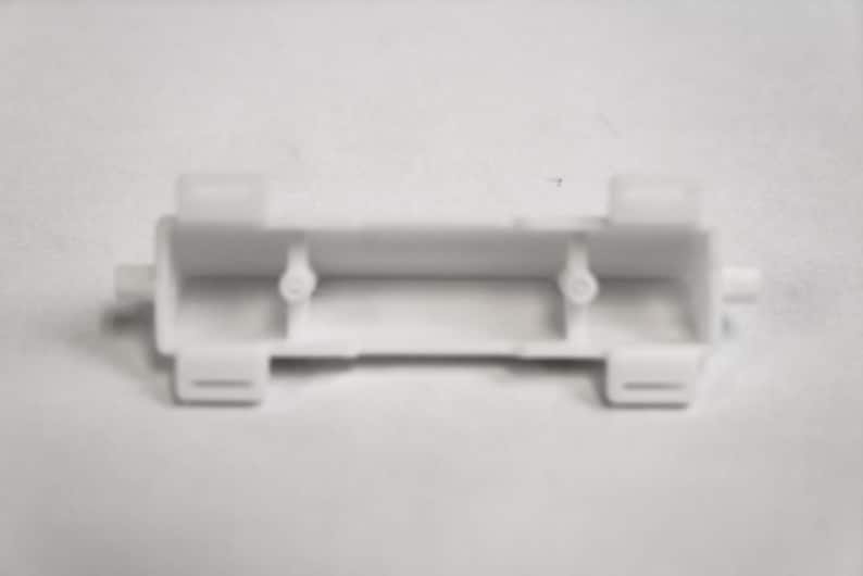 May include: White plastic battery holder with two compartments and tabs on either side.