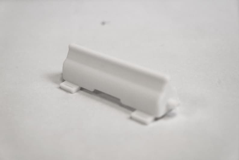 May include: White plastic road barrier with two small tabs on the bottom.