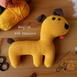 Puede incluir: Patrón de crochet para un juguete amigurumi de perro amarillo. El patrón está escrito en inglés e incluye instrucciones para hacer el cuerpo, la cabeza, las orejas, la cola y los ojos del perro. El patrón también incluye una lista de los materiales necesarios para hacer el juguete.